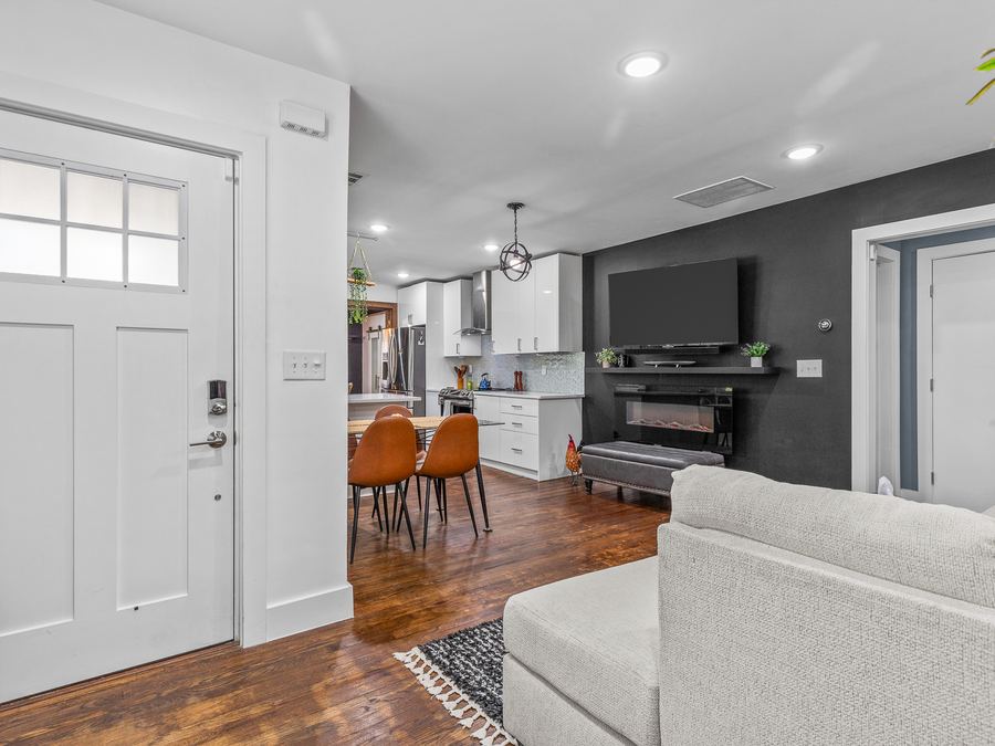 An open living room and kitchen with hardwood floors and a dark accent wall